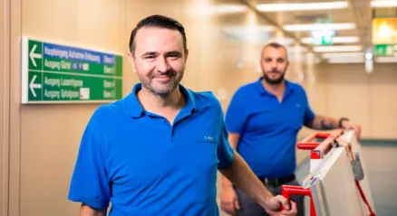 Two men are transporting a panel on a trolley through the hospital